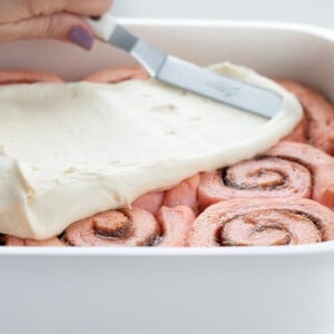 在粉色肉桂卷上撒糖霜。